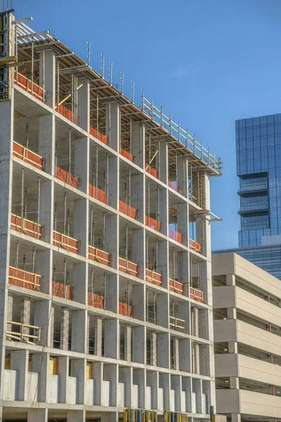 Austin Texas 'ta inşaat halindeki bitmemiş bir binanın dış görünüşü. Binanın içinde bir otopark ve modern cam gökdelen de mavi gökyüzüne karşı görülebilir..