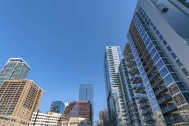 Austin, Teksas. Klasik ve modern gökdelenlerin ortası binaları olan şehir manzarası. Mavi gökyüzü arka planına karşı kurumsal binalarla birlikte balkonları olan konutlar var..