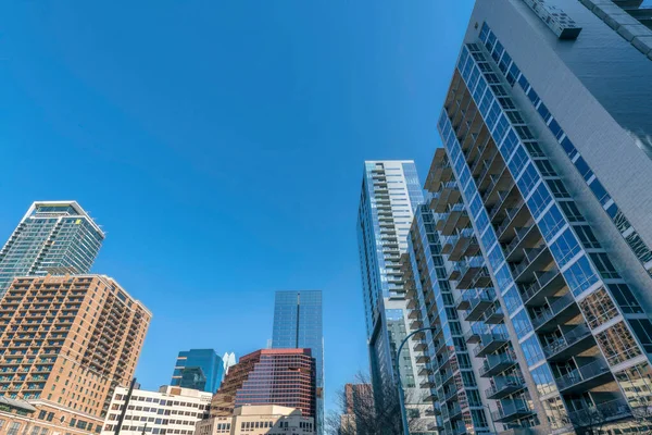 Austin, Teksas. Klasik ve modern gökdelenlerin ortası binaları olan şehir manzarası. Mavi gökyüzü arka planına karşı kurumsal binalarla birlikte balkonları olan konutlar var..