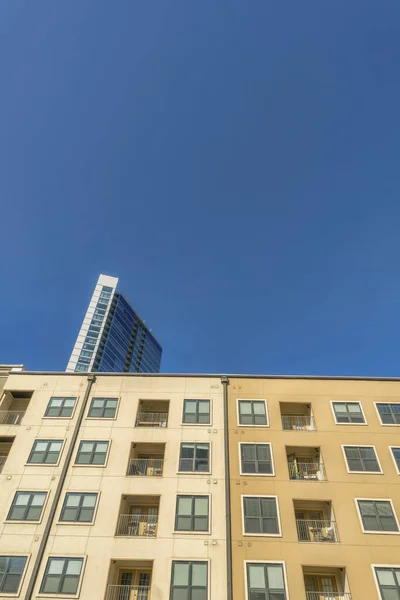 オースティン テキサス州 バルコニーとベージュ色のスキームを持つアパートの建物のファサード 超高層ビルや青空を背景に 窓のあるビルの低角度ビュー — ストック写真
