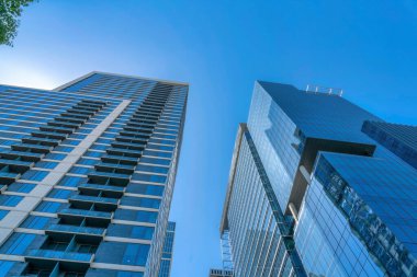 Austin, Teksas 'ta alçak açılı iki modern gökdelen. Binanın solunda balkonları sağında büyük sütunları olan bir bina var..