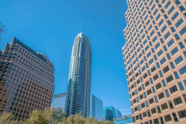 Austin, Teksas. Modern yüksek binaların ve konut binalarının manzarası. Önünde iki bina var. Fayans duvar kaplaması ve arkasında cam binalar var..