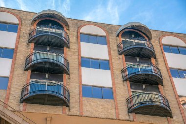 Tuğlalı tuğlalı ve balkonlu bir apartmanın alçak açılı görüntüsü San Antonio, TX. Kıvrımlı balkonları olan dış bina.