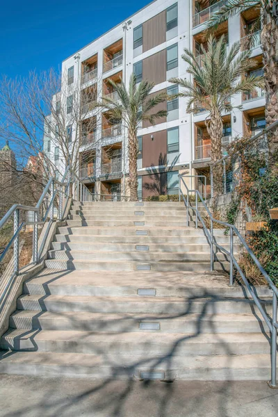 Staircase outside a low-rise apartment building at San Antonio, Texas. There are palm trees at the front of the building with balconies.
