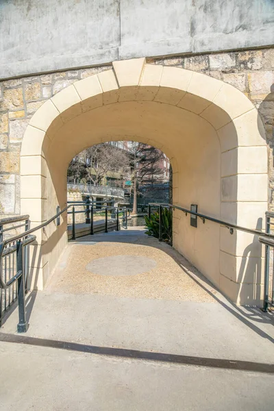 Arched underpass below the bridge at River Walk, San Antonio, Texas. Concrete pathway with metal handrails with a view of San Antonio River at the back.