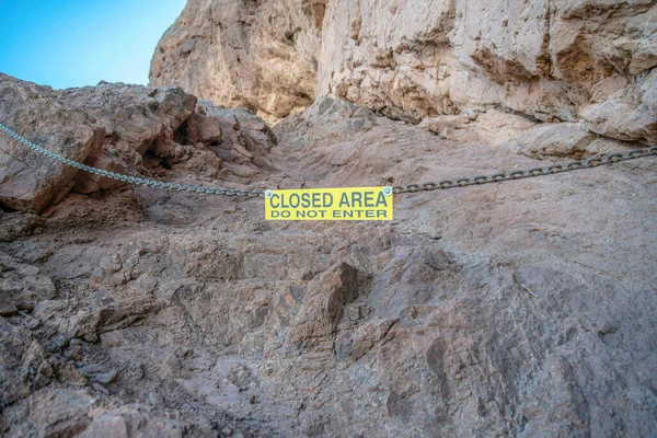 Phoenix, Arizona- Sign hanging on a chainlink against the rock mountain wall at Camelback Mountain. Yellow sign with Closed Area Do Not Enter.