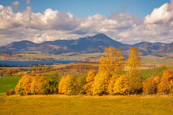 Осенний пейзаж с ярко окрашенными деревьями и холмами на заднем плане. Липтовский регион на севере Словакии, Европа.