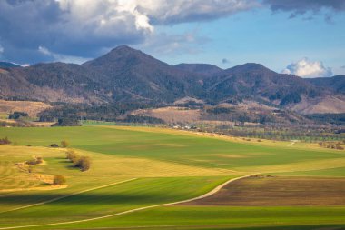 Güneşli bahar kırsal manzarası, tarlalar vadisi ve arka planda dağlar olan çayırlar. Slovakya, Avrupa 'daki Turiec Vadisi.
