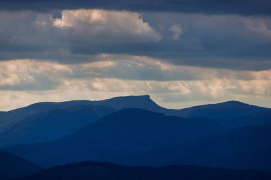 Arka planda dramatik gökyüzü olan dağ sırtlarının manzarası.