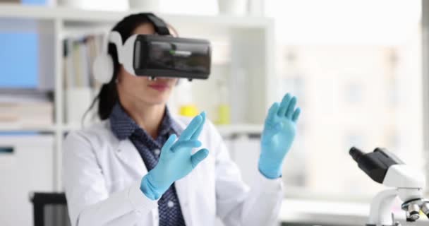 Жінка-біолог у окулярах віртуальної реальності махає руками в лабораторії 4k фільм — стокове відео