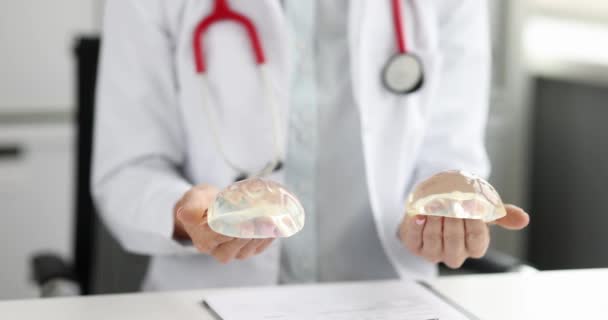 Doktor mamolog drží prsní silikonové implantáty ve svých rukou 4k film — Stock video