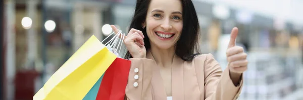 Mujer sonriente sosteniendo pulgares hacia arriba y bolsas de compras —  Fotos de Stock