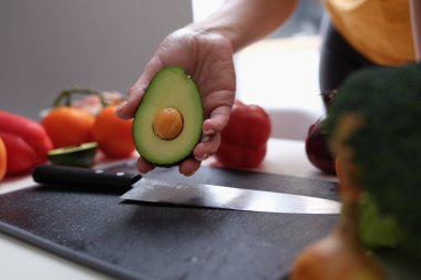 Kadının elinde olgun avokado bıçağı ve sebzeler var..