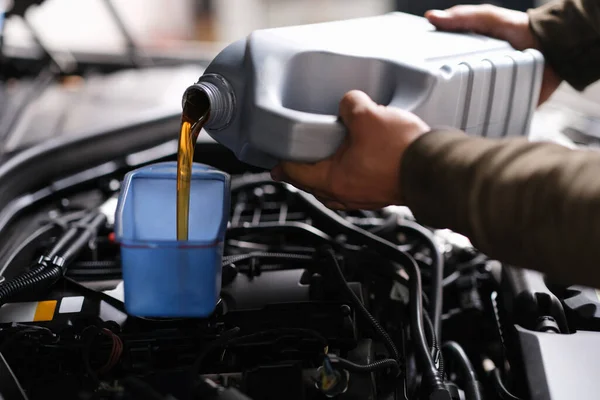 Mechanik ślusarz wlewa olej silnikowy do plastikowego pojemnika na silnik silnikowy — Zdjęcie stockowe