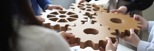 Efficient business team connects wooden gears into one