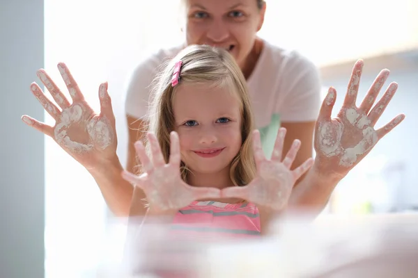 Menina e mãe mostrando suas palmas manchadas com farinha e sorriso — Fotografia de Stock