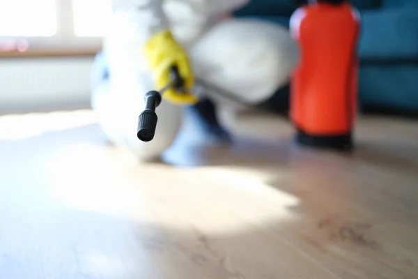 Uomo in tuta protettiva trattamento pavimento in appartamento con primo piano disinfettante — Foto Stock