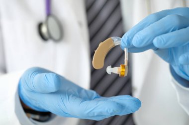 Doktor otorhinomoloğun elinde işitme cihazı var.