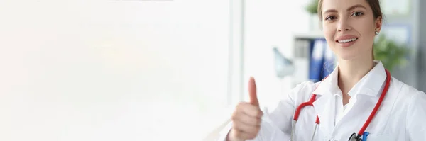 Улыбающаяся женщина-врач показывает большой палец в клинике — стоковое фото