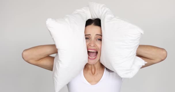 Young woman covering her ears with pillow and screaming 4k movie — Stock Video