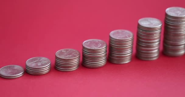 Stosy monet w porządku rosnącym i skarbonka stojąca na czerwonym tle 4k film — Wideo stockowe