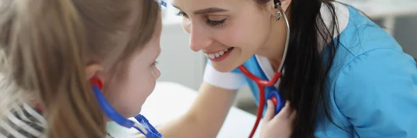 Docteur écoute avec stéthoscope à la petite fille et jouer avec elle à la clinique — Photo