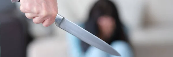 Homem agressivo segura faca na mão contra o fundo da mulher assustada — Fotografia de Stock