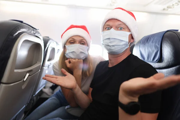 Uomini e donne tristi e ubriachi in maschere mediche protettive e berretti rossi di Babbo Natale che volano in aereo — Foto Stock