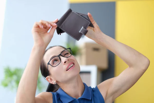 Gözlüklü genç bir kadın boş deri cüzdana bakıyor. — Stok fotoğraf