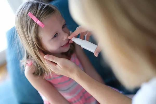 Мати набиває маленький дівочий ніс антибактеріальними краплями вдома — стокове фото