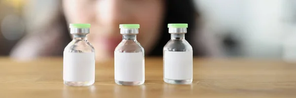 Vrouw kijkt naar de fles vaccin en beslist welke te kiezen — Stockfoto