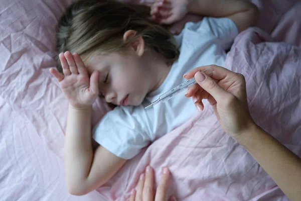 Mama măsoară temperatura corpului unei fetițe bolnave întinsă în pat — Fotografie, imagine de stoc