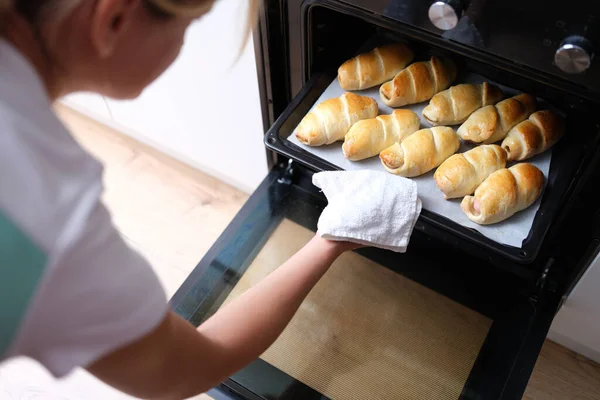 Mulher tira assadeira de croissants cozidos do close-up do forno — Fotografia de Stock
