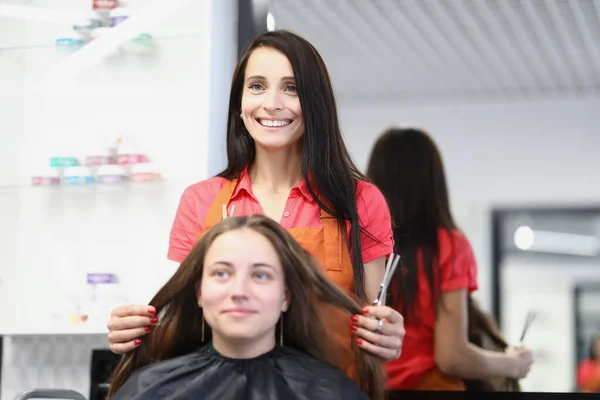 Młoda klientka siedzi na krześle przed fryzjerem w salonie piękności — Zdjęcie stockowe
