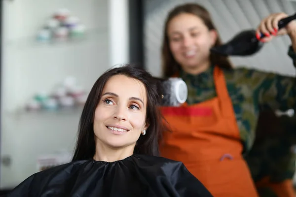 Женщина парикмахер сушки и выпрямления волос клиента с щеткой и феном — стоковое фото