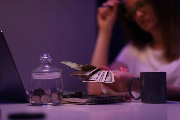 Mujer triste sentada en la mesa en la habitación oscura y contando dinero para las facturas de servicios públicos de primer plano — Foto de Stock