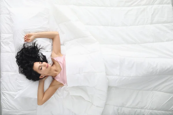 Young woman with curly hair sleeping in white bed top view — Stock Photo, Image