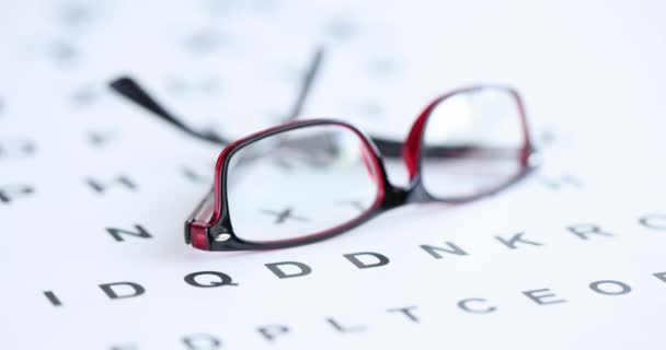Óculos em quadros vermelhos pretos deitado na mesa de exame de olho filme 4k — Vídeo de Stock