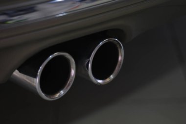 Siyah gövdeli ve gri plastik parçalı güçlü spor arabanın ikiz krom egzoz borusu.