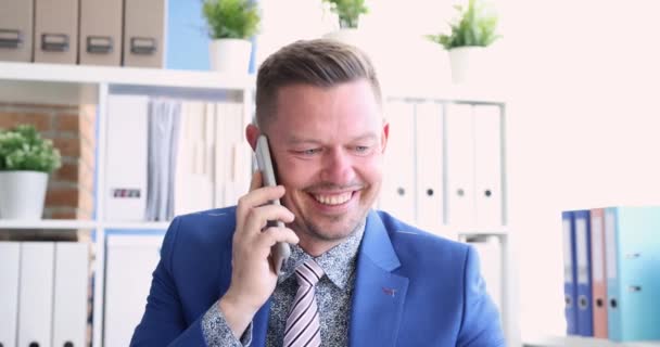 Joven hombre de traje hablando en el teléfono celular en la oficina y sonriendo película 4k — Vídeos de Stock