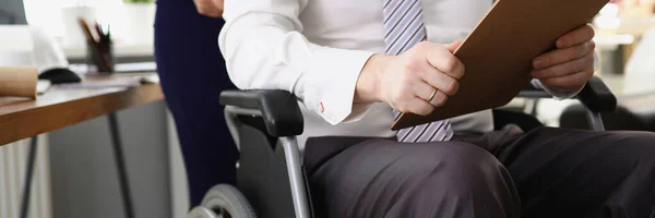 Sekretärin rollt CEO im Rollstuhl mit Dokumenten und Berichten in den Händen — Stockfoto