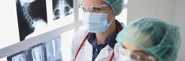 Dos doctores con máscaras protectoras médicas examinando rayos X médicos —  Fotos de Stock