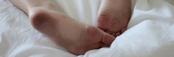 Sucios pies masculinos yacen en la cama blanca limpia — Foto de Stock