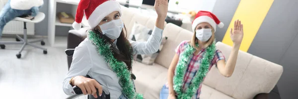 Mulher com deficiência em cadeira de rodas e amigo em máscara médica cumprimentando Natal em casa e acenando — Fotografia de Stock