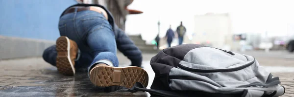 Homem com mochila deitada na calçada escorregadia após queda close-up — Fotografia de Stock