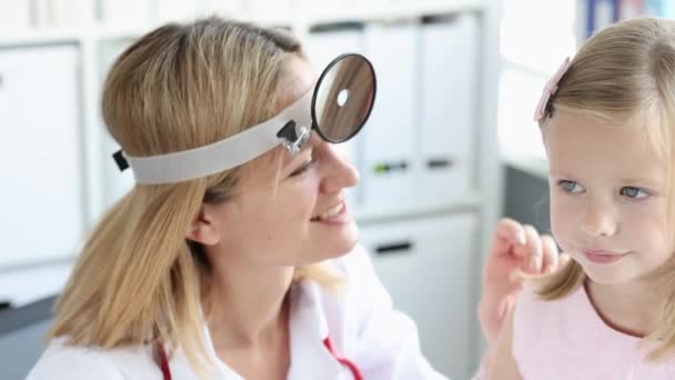 Mujer ENT lleva a cabo el examen físico de la oreja con otoscopio de la niña 4k película — Vídeo de stock