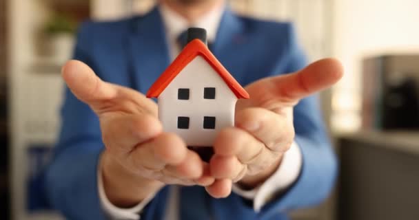 Hombre agente de seguros sostiene pequeña casa en manos 4k película — Vídeo de stock