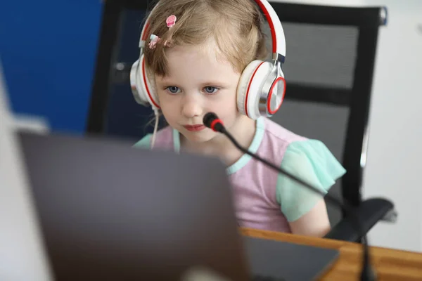 Criança com fones de ouvido olha para a tela do laptop — Fotografia de Stock