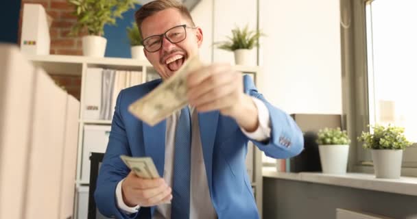 Young happy businessman counting dollar bills and scattering them in office 4k movie — Stock Video