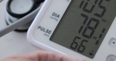 Kadın arteriyel kan basıncını otomatik tansiyon monitörü 4K filminde ölçüyor.